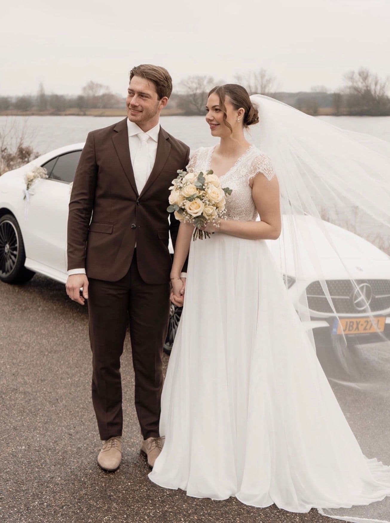 Bruidspaar bij de trouwauto.