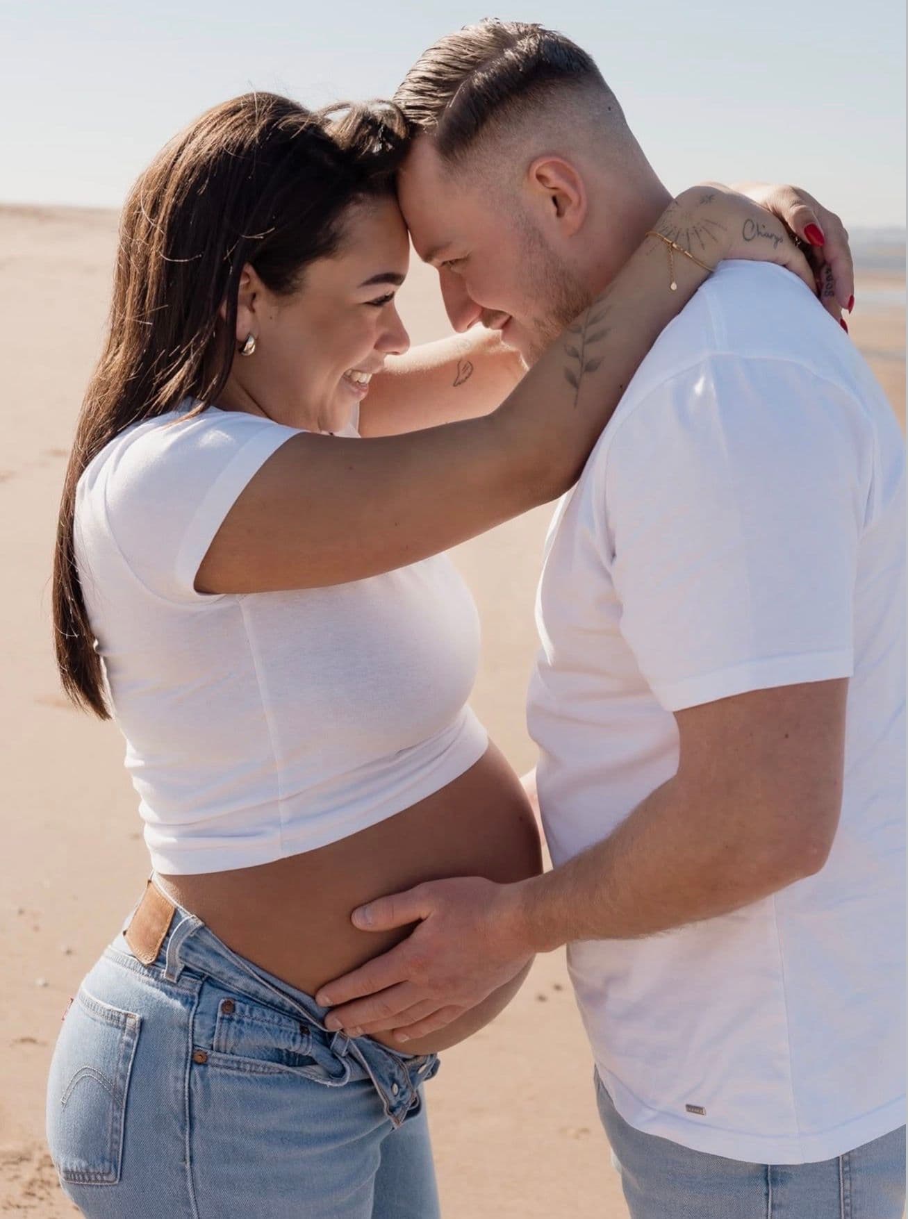Zwangerschapsshoot aan het strand in het wit.